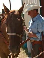 Warden Brown in plainclothes next to his brown horse, while wearing a cowboy hat