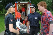 Melanie (Sanna Englund, l.) und Mattes (Matthias Schloo, M.) ermitteln, wie es zu dem Streit zwischen dem Friedhofsgärtner Oliver Carell (Daniel Alexander, r.) und der Friedhofsbesucherin Elli Pellenwessel (Heidy Forster, 2.v.l.) kommen konnte. Dr. Haase (Fabian Harloff, M.) kümmert sich um die verletzte ältere Dame.