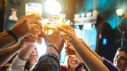 Group of happy friends drinking and toasting beer at brewery bar restaurant - Friendship concept with young people having fun together at cool vintage pub - Focus on middle pint glass - High iso image