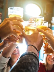 Group of happy friends drinking and toasting beer at brewery bar restaurant - Friendship concept with young people having fun together at cool vintage pub - Focus on middle pint glass - High iso image