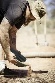Man holding a pot with dirt in it.