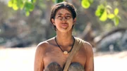 Cassidy wearing a coconut bra and fabric bikini bottoms standing on the beach in the Philippines.