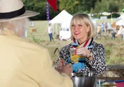 Agatha Raisin (Ashley Jensen) schenkt auf dem Carsely-Fest Getränke aus und hat dabei große Freude.