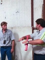 Kevin and another man near the jet in the hangar.