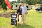 Couple Ken and Anita Corsini smile in front of the house they flipped as seen on Flip or Flop Atlanta