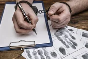 Men's hands with handcuffs fill the police record, confession.