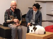 Jackson Galaxy petting a cat in the cafe.