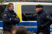 Robert Björkemyr (Filip Berg, l.) und Johan Jansson (Anders Berg, r.) stehen am Einsatzwagen. Johan ist der Chef von Kati.