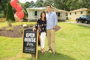 Couple Ken and Anita Corsini smile in front of the house they flipped as seen on Flip or Flop Atlanta