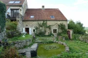 The contributors' property has a lovely backyard that comes with old masonry, a pond, and overgrown plants and ivy around the perimeter, as seen on HGTV's House Hunters International Renovation.