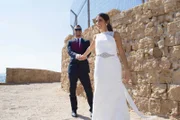 ALEXEI BROVARNIK and LOREN BROVARNIK smile as they pose for a wedding photograph.