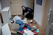 Paul Dänning (Jens Münchow, r.) findet den Studenten Faza (Komparse) zusammengeschlagen in seiner verwüsteten Wohnung.