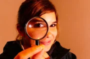 Anna nimmt eine Haselnuss unter die Lupe: Wurde die von der Haselmaus geknackt? Sie erkennt es an einem kreisrunden Loch mit einer schräg geknabberten Kante.