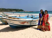 Frauen in Saris vor Fischerbooten am Strand von Trincomalee.