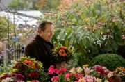 Beissl (Andreas Giebel) kauft seiner Frau einen Blumenstrauß.