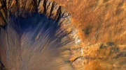 Auf der Oberfläche des Mars befindet sich Staub aus Eisenoxid, der dem Planeten seine rötliche Färbung verleiht. Die bläulichen Bereiche in den Kratern entstehen durch Ablagerung basalthaltigen Sandes.