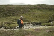 Ein Moorexperte steht in Schottland an einem Gewässer im Moor.