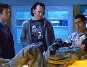 V.l.: Fasziniert stehen Woody (Jerry O'Connell), Nigel (Steve Valentine) und Bug (Ravi Kapoor) vor der freigelegten Leiche eines eingefrorenen Piloten.