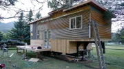 Phil and Shane have built the deck in the front of the tiny house and are working on the metal siding, for Fisher tiny house build, in Swan Valley, Idaho, as seen on Tiny House, Big Living.