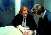 Scully (Gillian Anderson, l.) will Mulder (David Duchovny, r.) eine Phosphoressenz um Mund und Nase einer ermordeten Prostituierten zeigen, die sie bei ihrer ersten Untersuchung entdeckt hat.