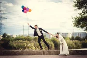 Groom flies on the balloons, but the bride holds his hand. Funny wedding.