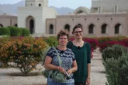 Momo und Patty, Mutter und Tochter, Passagiere auf der Weißen Lady, bei ihrem Ausflug zur Großen Sultan-Qabus-Moschee in Muscat/Oman. Sie stehen vor der Moschee in dem dazu perfekt angelegten Blumengarten.