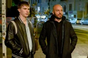 Marco Stiehler (Gustav Schmidt, links) und Mads Andersen (Dar Salim, rechts) beobachten, wie ein Verdächtiger abtransportiert wird.