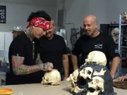 DJ Ashba fait un autographe sur un crâne dans la boutique de Denny, sous le regard de Brett et Denny.