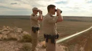 Aaron Sims and Stewart Rogers look through binoculars.
