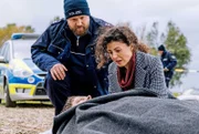 Corina Loose (Liza Tzschirner, re) findet am Tatort nur noch die Leiche ihres Mannes. Der Polizeiobermeister (Moritz Sachs, li) versucht, sie zu trösten.