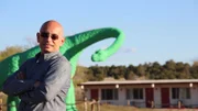 Host Anthony Melchiorri poses in front of a dinosaur statue outside the Grand Canyon Caverns on Historic Route 66, as seen on Travel Channel's Hotel Impossible.