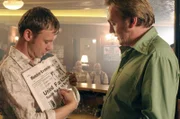 Sam Tyler (John Simm, l.) zeigt Gene Hunt (Philip Glenister, r.) den Zeitungsartikel über den Mord an einem Manchester United-Fan …