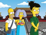 Selma (M.) entschließt sich, ein Kind zu adoptieren. Und da dies am einfachsten in China sein soll, fliegt sie mit der gesamten Familie Simpson nach Peking, wobei Homer (l.) sich als ihr Ehemann ausgeben muss ...