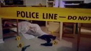 Ein Tatort in einer Küche mit einem Mordopfer auf dem Boden, bedeckt mit einem Laken. Waffe, Kugeln, Polizeiband und Lichter.