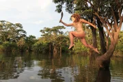Gia jumps into water with a survival tool.