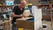 In the workshop contestant Robert applies white paint to the front of his unhinged project. As seen on HGTV's Flea Market Flip