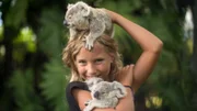 Izzie holding two koalas smiling at the camera.