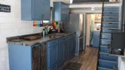 The blue kitchen cabinets bring in a good pop of color to the white washed interior, for Steve and Holly Schuett's tiny house build, in Gleason, Wisconsin, as seen on Tiny House, Big Living.