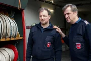 Die Feuerwehrleute Arne Paulsen (Guido Renner, l.) und Carsten Bruns (Patrick von Blume, r.) sind schockiert, als sie hören, wer nachts in dem gelöschten Fahrzeug verbrannt ist. Was hatten die beiden mit dem Toten zu tun?