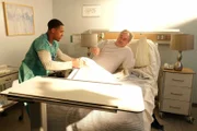 Krankenpfleger Gino Brown (Cameron J. Armstrong) versorgt den Patienten Cambis Borrin (John Billingsley).