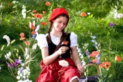 Rotkäppchen (Kathleen Frontzek) freut sich über die Blumenpracht im Wald. Sie will der kranken Großmutter einen schönen Strauß bringen.