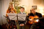 Tochter Anna-Maria (jung, Liva Steger), Sohn Stefan (jung, William Boer) und Reinhard (Oliver Törner), der neue Freund von Mutter Brigitte singen Weihnachtslieder.