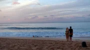 Ein Surfer schaut sich die Wellen an bevor es ins warme Wasser geht. Am Sunset Beach an der North Shore.