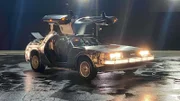 Side profile, DeLorean with doors open, outside in parking lot at night