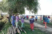 Fast alle Dorfbewohner helfen, das Baumaterial zum Ufer zu bringen.  +++