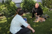 Cesar im Gespräch mit Anna und Zach, während sie mit Bär neben ihnen im Gras sitzen. (National Geographic)