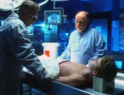 Grissom (William Petersen, l.) und Dr. Robbins (Robert David Hall) untersuchen die Leiche und stellen fest, dass der Junge zwar überfahren wurde, die Todesursache jedoch eine andere war.