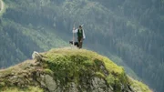 Auf einem Hügel steht ein Hirte mit seinem Collie