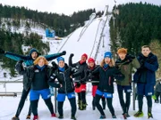 V.l.: Esra, Zoe, Vanessa, Lars, Heidi, Tove, Maddox und Henry vor der großen Skisprung-Schanze in Oberhof