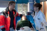 Notarzt Haase (Fabian Harloff, l.) bringt Nadine Weinert (Eva Löser, M.) mit den Anzeichen einer Methanolvergiftung ins EKH zu Jasmin (Gerit Kling, r.).